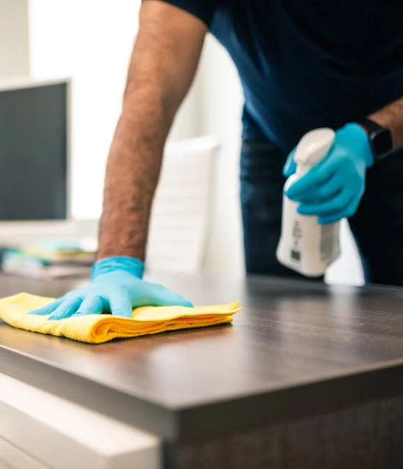 housekeeper wiping down table surface